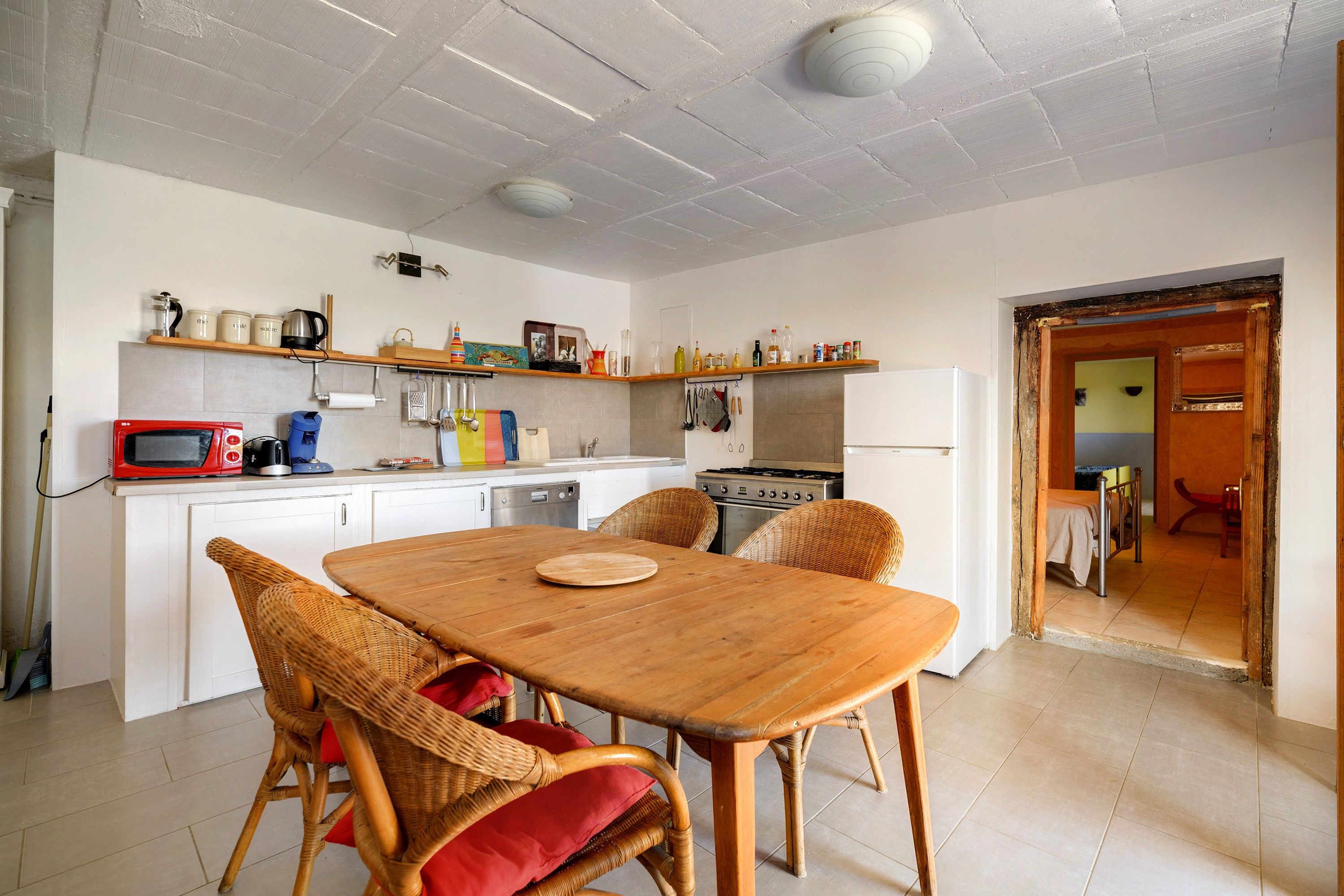 Una cocina con mesa, sillas y diversos electrodomésticos.