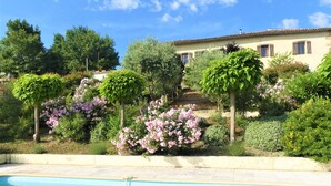 A swimming pool with a clear blue water surface, surrounded by lush greenery and flowering plants. - Holiday Home “Maison Cazac” with Mountain View and Wi-Fi (Cazac)