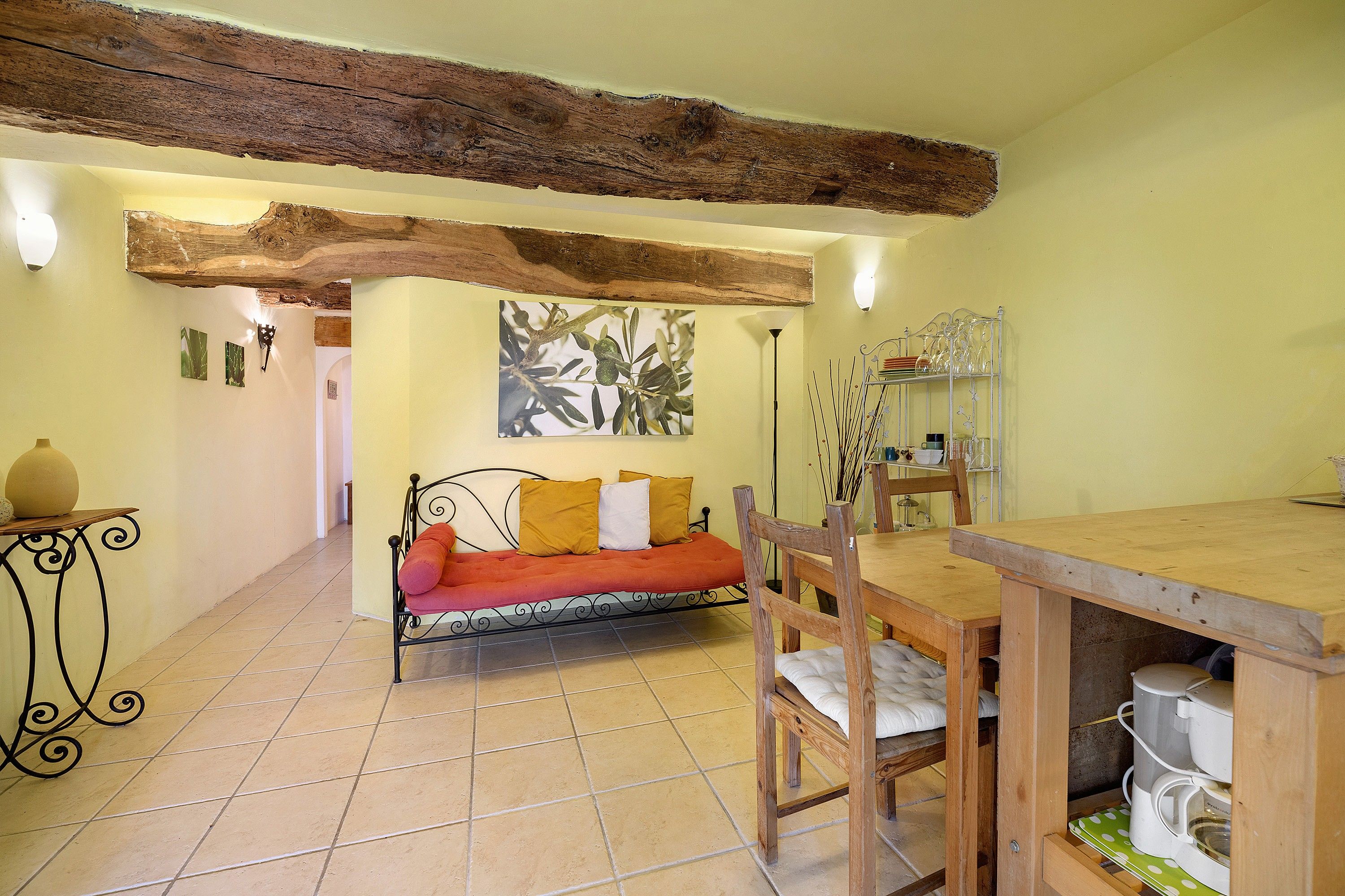 Una habitación acogedora con una mesa de comedor de madera, un sofá con cojines y un suelo de baldosas.