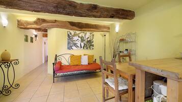 Una habitación acogedora con una mesa de comedor de madera, un sofá con cojines y un suelo de baldosas.