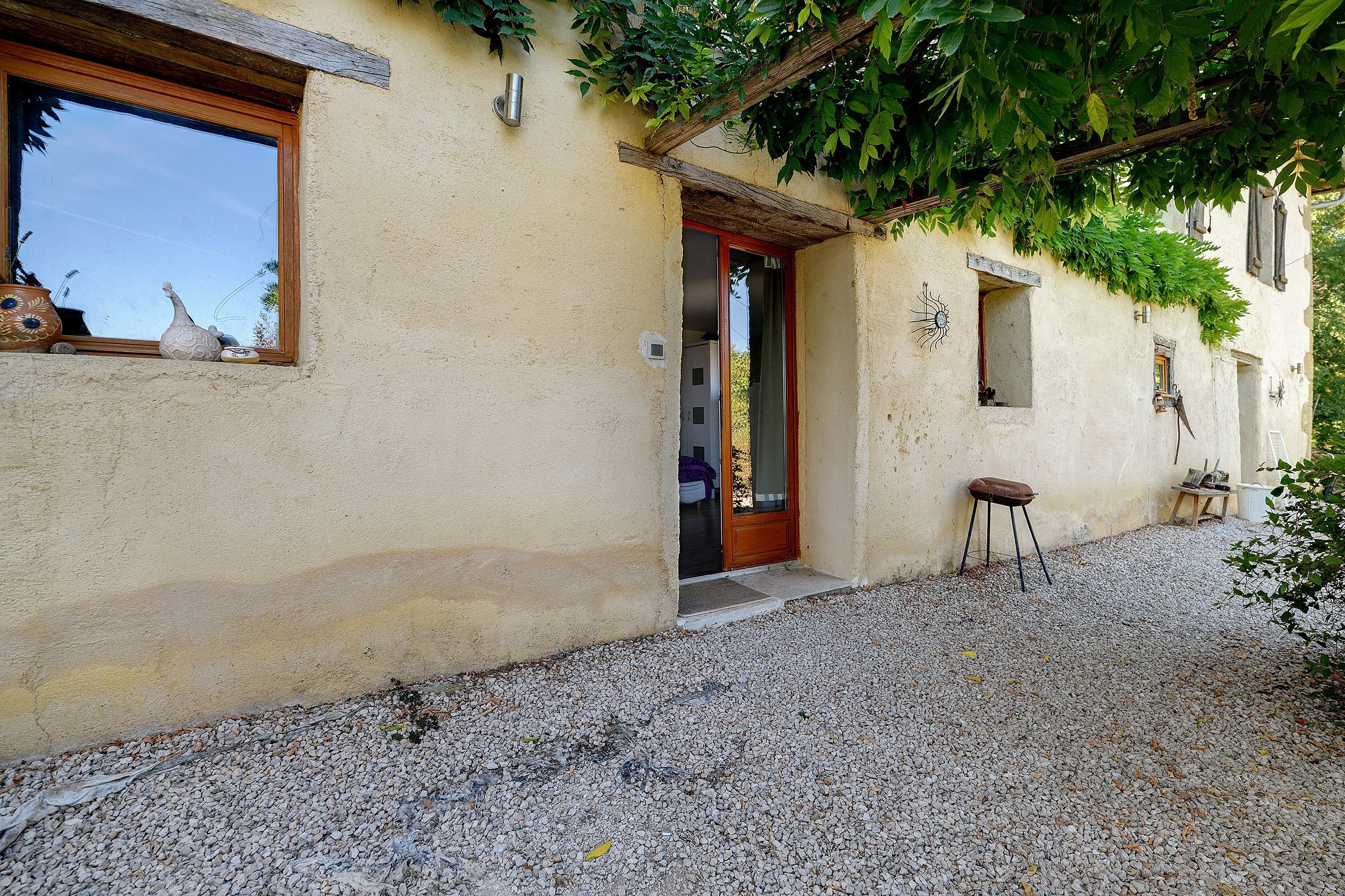 Un bâtiment rustique avec une allée en gravier, un banc en bois et une petite table.