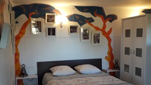 Une chambre à coucher comprenant un lit, des tables de chevet, une armoire et des cadres photos accrochés au mur.