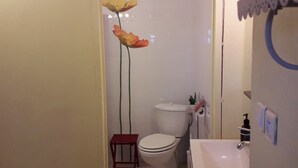 Une salle de bain équipée de toilettes, d’un lavabo et d’une grande plante décorative.