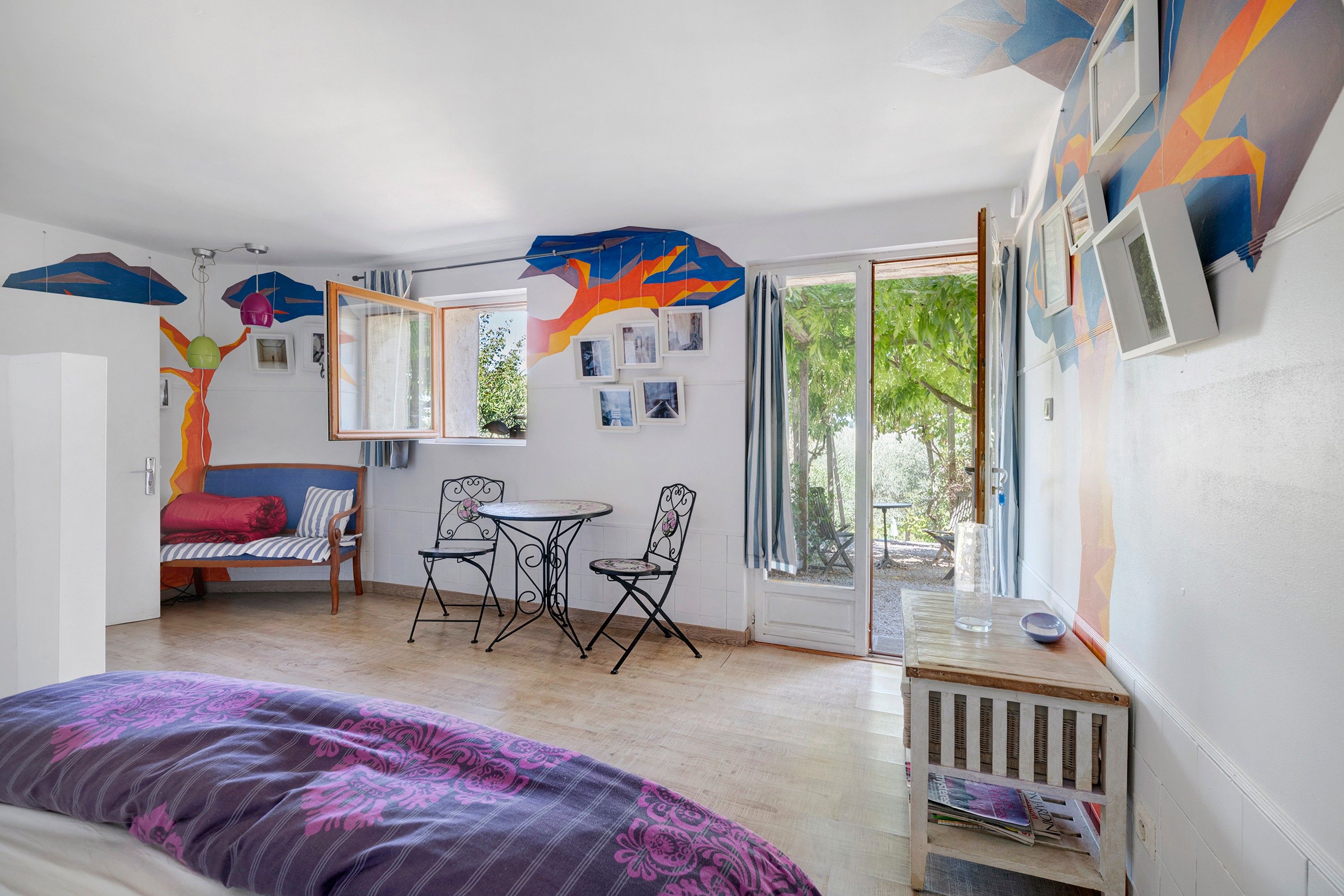 Une pièce comprenant un lit, un canapé, une table à manger avec des chaises et une grande fenêtre donnant sur un paysage verdoyant.