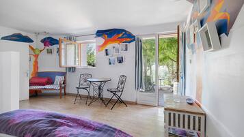Une pièce comprenant un lit, un canapé, une table à manger avec des chaises et une grande fenêtre donnant sur un paysage verdoyant.