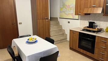 Una cucina con mobili in legno, un tavolo da pranzo con sedie, una mappa appesa al muro e un fornello.