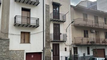 Un immeuble à plusieurs étages doté de balcons, d’une porte de garage rouge et situé dans une rue pavée.