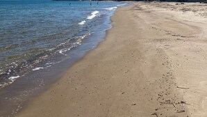 A sandy beach with a clear blue sky, a calm sea, and buildings in the background. - La Fontanella - Authentic Sicilan Retreat (Ciminna)