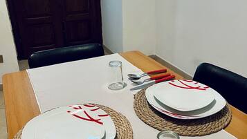 Une table à manger dressée avec des assiettes, des couverts et un verre.