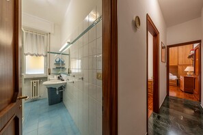 Een badkamer met een wastafel, spiegel en raam voorzien van gordijnen.