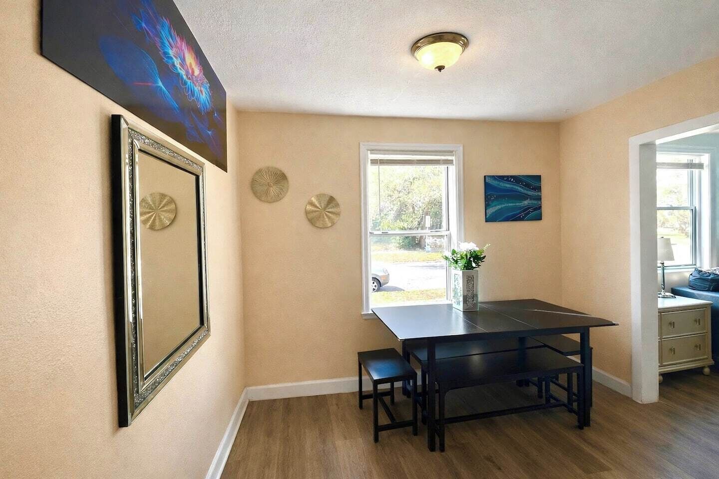 A dining area with a table and chairs, a window with a view, and decorative wall art.