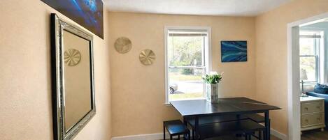 A dining area with a table and chairs, a window with a view, and decorative wall art.