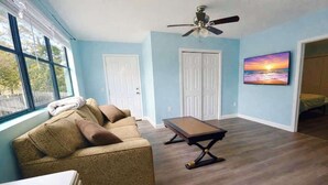 A room with a sofa, a table, and a ceiling fan. - The Big Blue Mesmerizing Mirror Home- 6 Mins to DT (Jacksonville)