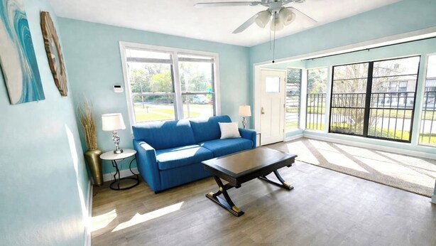 A room with a blue sofa, a coffee table, a lamp, and a ceiling fan. - The Big Blue Mesmerizing Mirror Home- 6 Mins to DT (Jacksonville)