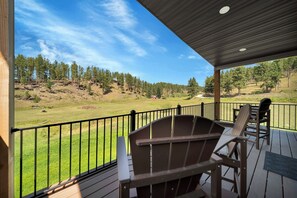 Um terraço coberto com vista para um campo gramado e árvores.