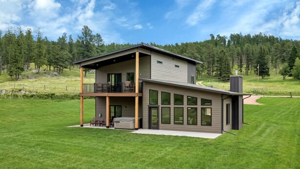 Ein zweistöckiges Haus mit Balkon, großen Fenstern und einem Whirlpool im Garten.