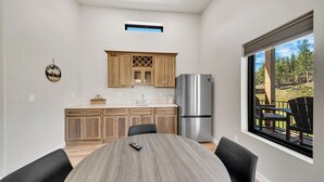 Eine moderne Küche mit Holzausstattung, einem Edelstahlkühlschrank und einem Esstisch mit Stühlen.