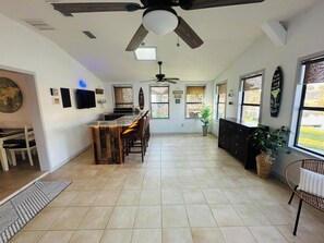 A spacious kitchen with a bar area, large windows, and a ceiling fan. - 3-bedroom house in serene Port Orange with a quiet neighborhood. (Port Orange)