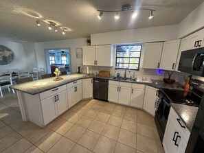 A modern kitchen with white cabinets, a granite countertop, and a stainless steel dishwasher. - 3-bedroom house in serene Port Orange with a quiet neighborhood. (Port Orange)