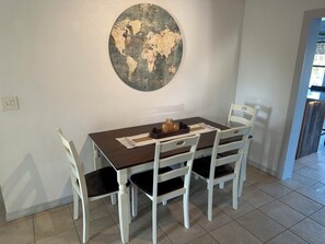 A dining area with a round wall map, a wooden table, white chairs, and a small decorative tray. - 3-bedroom house in serene Port Orange with a quiet neighborhood. (Port Orange)
