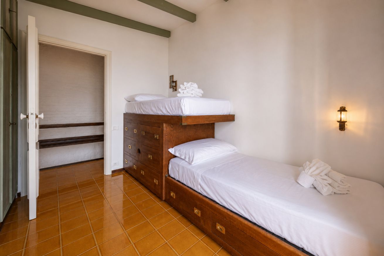 Un dormitorio con una cama de madera, un aparador y una lámpara fijada a la pared.