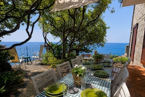 Un espace de restauration en plein air avec une table dressée pour quatre personnes, offrant une vue sur la mer.