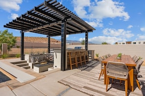 A covered outdoor patio with a barbecue area, seating, and a view of the mountains. - Red Rock Isle: Private Pool + Hot Tub! Games! (Washington)