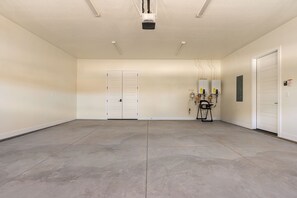 A spacious, empty room with a concrete floor, white walls, and a ceiling with recessed lighting. There are two white doors, a whiteboard, and a black chair with wheels. - Red Rock Isle: Private Pool + Hot Tub! Games! (Washington)