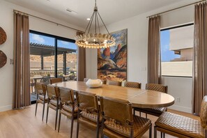 A dining area with a round table, leather chairs, and a chandelier. - Red Rock Isle: Private Pool + Hot Tub! Games! (Washington)