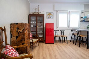A room with a wooden cabinet, a red refrigerator, and a dining area with chairs and tables. - New Room 1 near Venice | Private Bathroom and AC (Malcontenta)