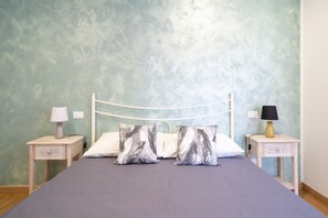 A bed with a white metal frame, two nightstands with lamps, and a textured wall.
