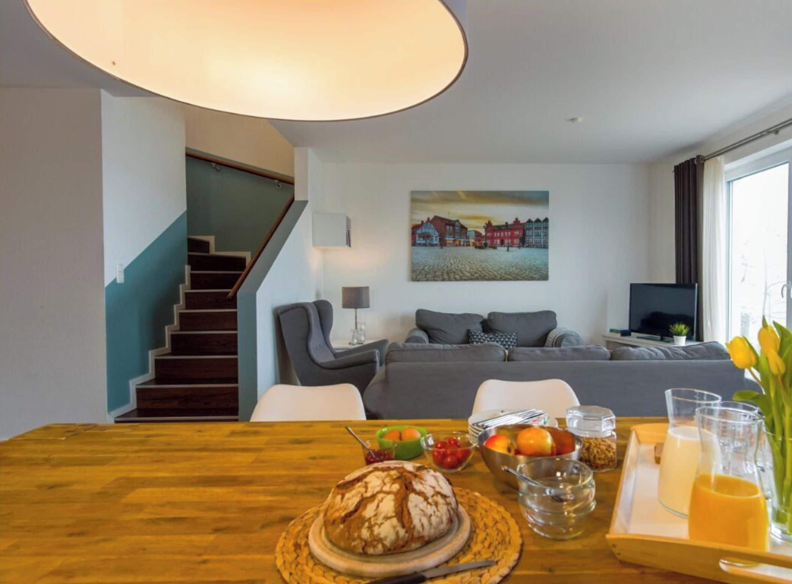 A modern living room with a wooden dining table, a sofa, and a painting on the wall.