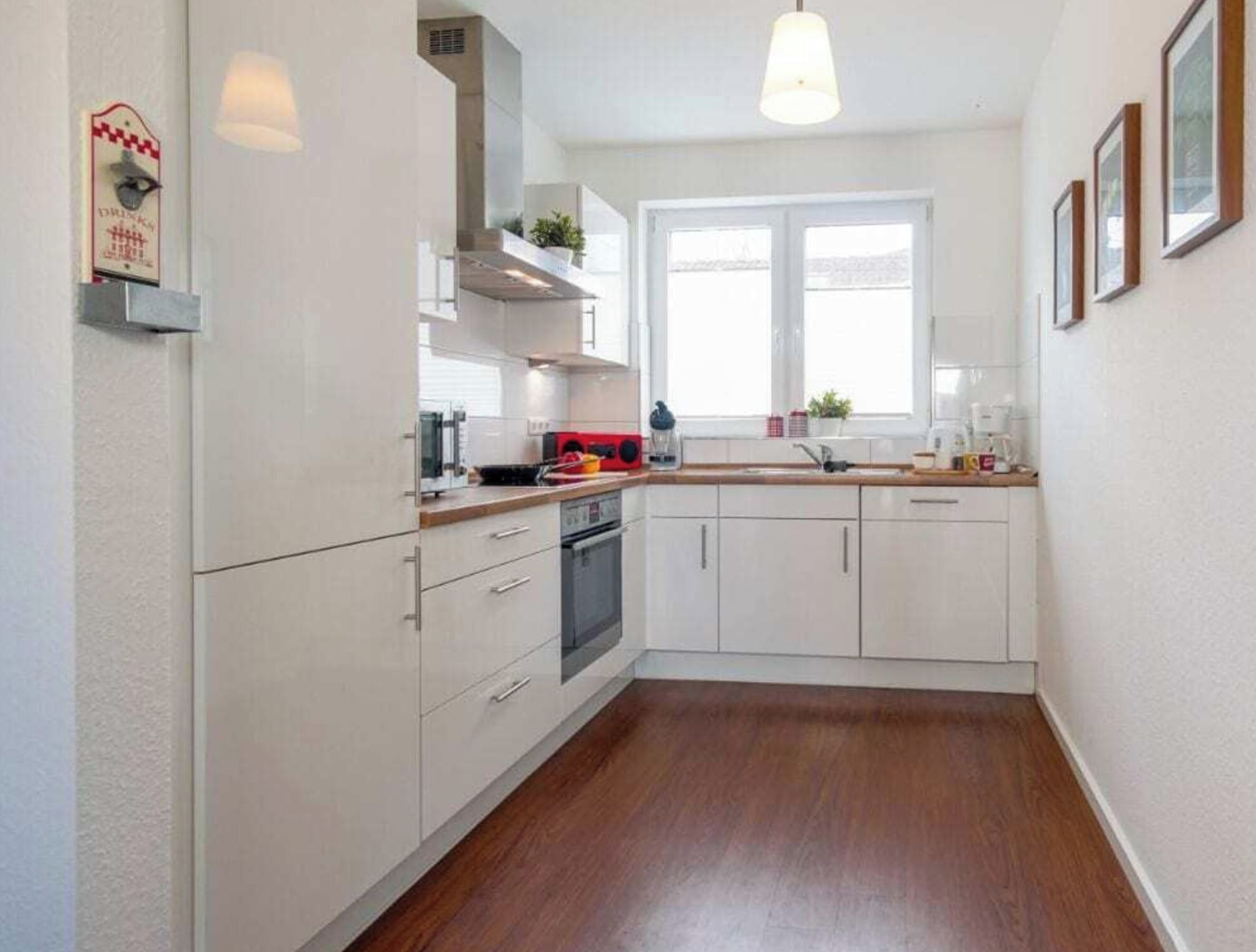 A kitchen with white cabinets, a wooden countertop, a built-in oven, and a window providing natural light.