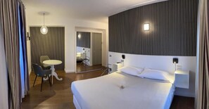 A hotel room with a large bed, bedside tables, a desk with a chair, and a mirror. - IL VECCHIO BORGO RELAIS (Como)