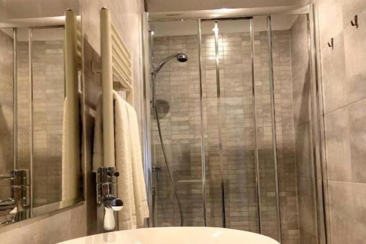 A modern bathroom with a large oval sink, a glass shower enclosure, and a mirror.