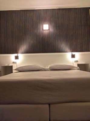 A hotel room with a bed, two bedside lamps, and a wall with vertical slats. - IL VECCHIO BORGO RELAIS (Como)
