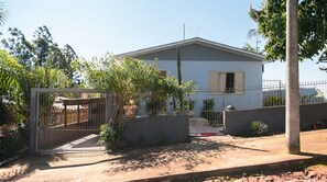 A residential house with a gated entrance, a small porch, and a concrete driveway. - Casa com 3 Quartos Wi-fi e Quintal no Centro (Santa Rosa)