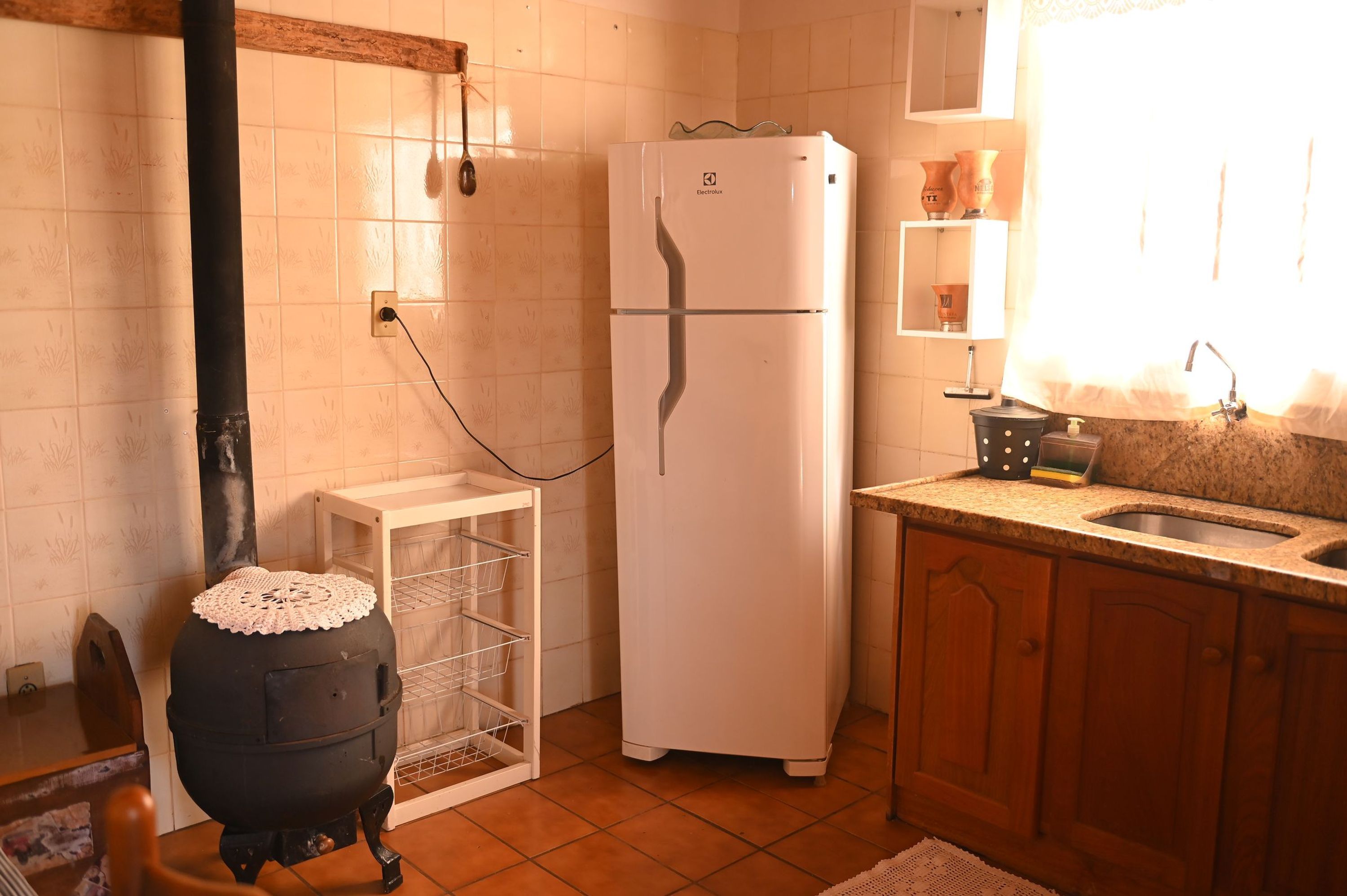 Cozinha com fogão preto, geladeira branca e armário de madeira.