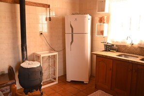 A kitchen with a black stove, white refrigerator, and a wooden cabinet.