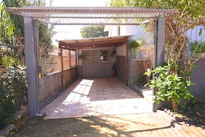 A covered patio area with a pergola, a wooden door, and a potted plant. - Casa com 3 Quartos Wi-fi e Quintal no Centro (Santa Rosa)