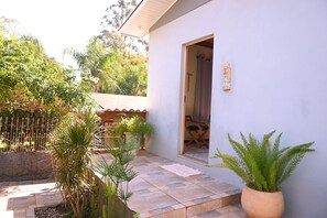 A residential property with a tiled patio, potted plants, and a wooden fence. - Casa com 3 Quartos Wi-fi e Quintal no Centro (Santa Rosa)