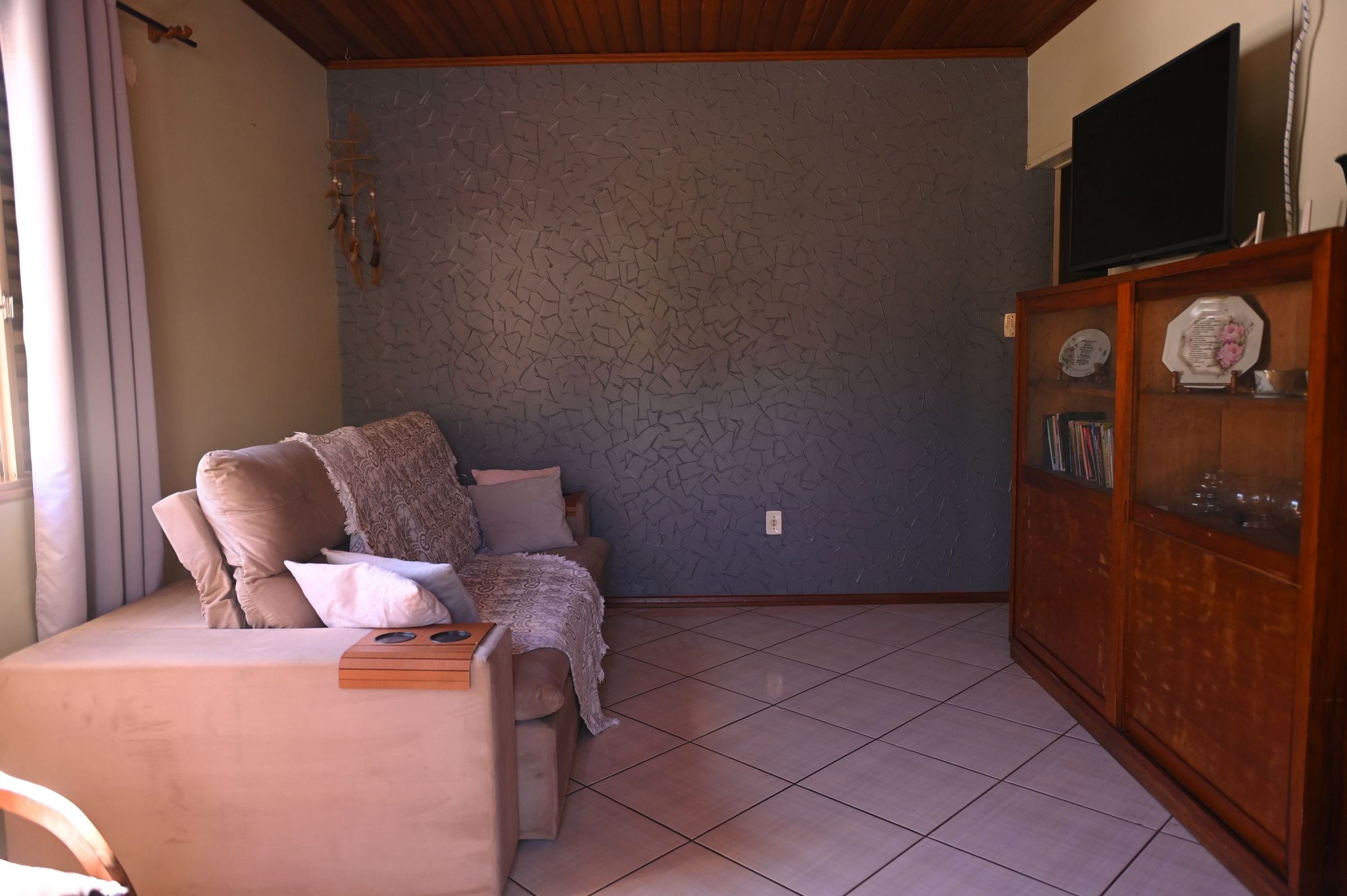 A living room with a sofa, a television on a stand, and a cabinet with decorative items.