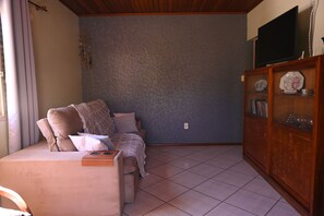 Un saló amb un sofà, una televisió sobre un moble baix i un armari amb objectes decoratius.
