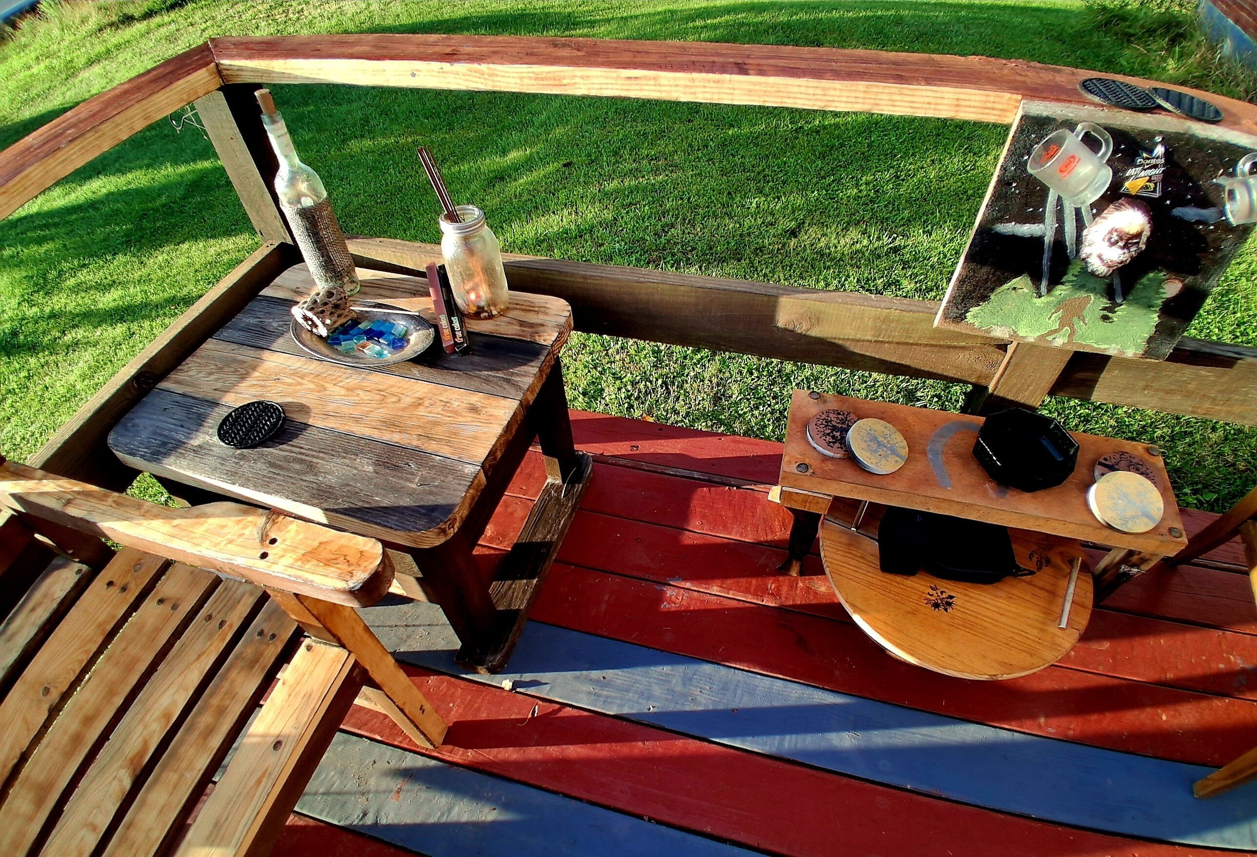 Una terraza de madera con una mesa, una silla y una pequeña fuente.