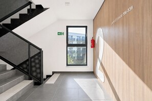 A modern interior with a staircase, a fire extinguisher, and a window with a view of buildings. - Bubble Love Suites - Jacuzzi & Parking  (Gdańsk)