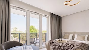 Een hotelkamer met een bed, een tafel met een boek, een balkon met stoelen en een moderne lamp.