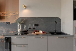 A modern kitchen with a marble backsplash, a wine glass set, and a cheese board. - Bubble Love Suites - Jacuzzi & Parking  (Gdańsk)