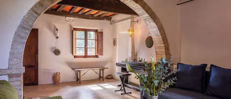 A cozy room with a stone archway, a wooden table, a sofa, and a vase with plants.