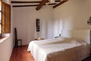 Ein Schlafzimmer mit einem Bett, einem Sessel, einem kleinen Tisch und einem Fenster.