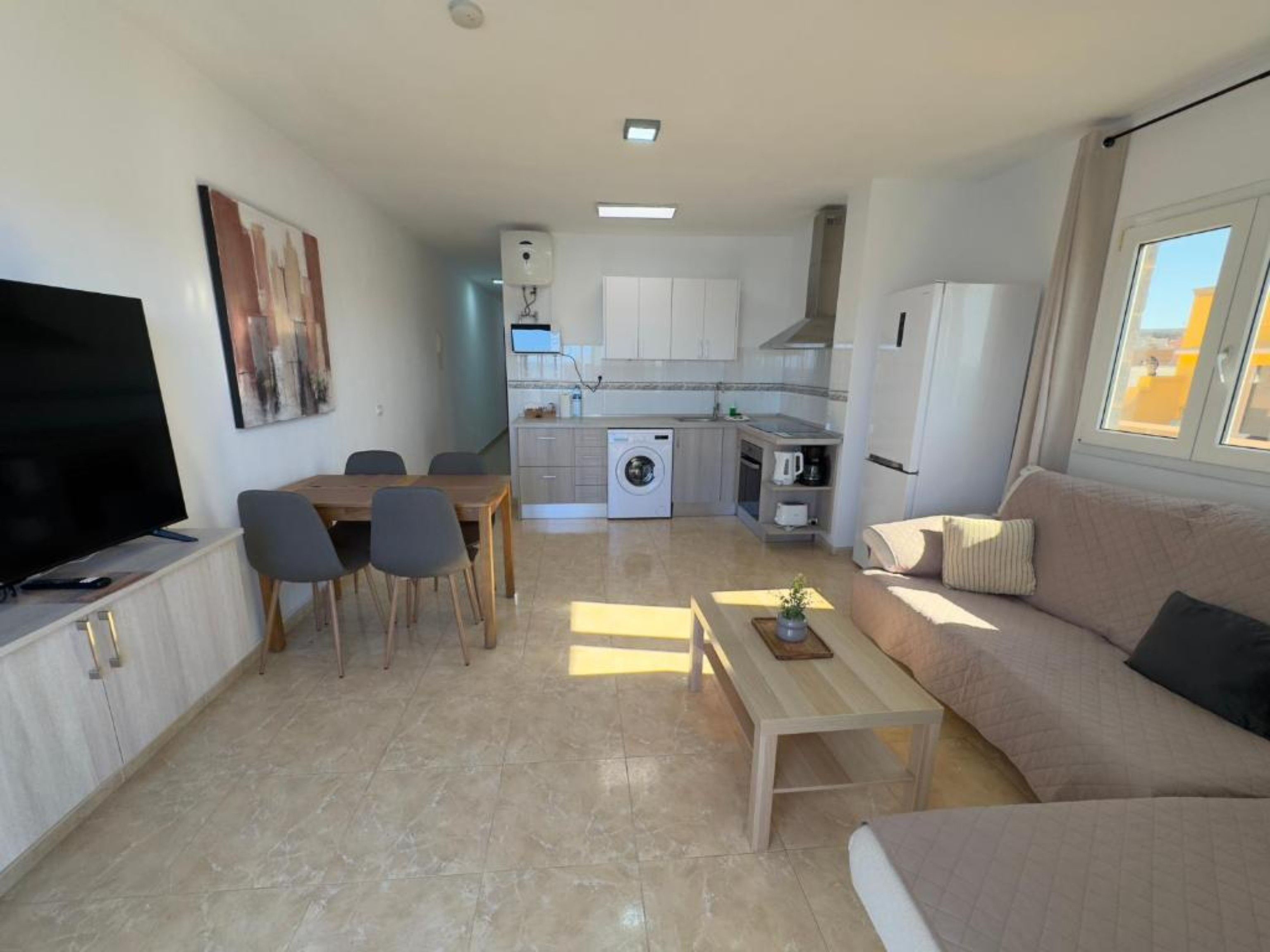Een ruimtelijke leefruimte met een eethoek, kitchenette en een bank.
